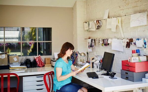 Femme en télétravail devant son cahier et son ordinateur à côté d'une Imprimante multifonction Xerox C315.