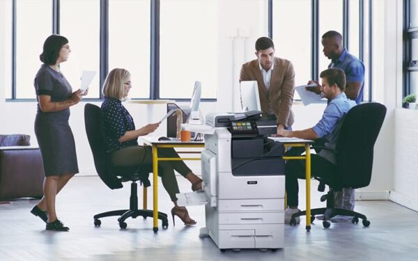 Equipe de travail dans un bureau avec des papiers imprimés et l'imprimante multifonctions couleur Xerox® Série VersaLink C7100